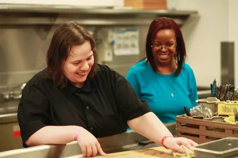A developmentally disabled woman works in the kitchen with a DSP worker from ALSO.